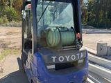 a fork truck that is parked next to a pile of wood