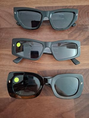 trois paires de lunettes de soleil noires posées sur une surface en bois