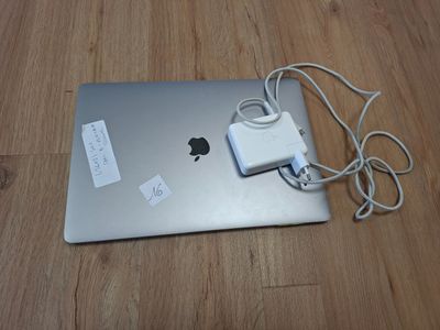 a laptop with a charger attached to it on a wooden floor