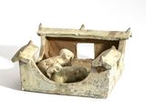 une petite statue représentant un chien dans un bateau, posée sur une surface blanche