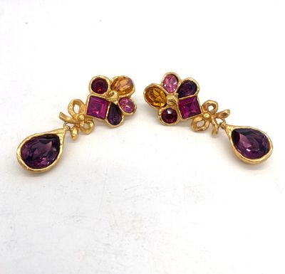 une paire de boucles d'oreilles ornées de pierres violettes sur un fond blanc