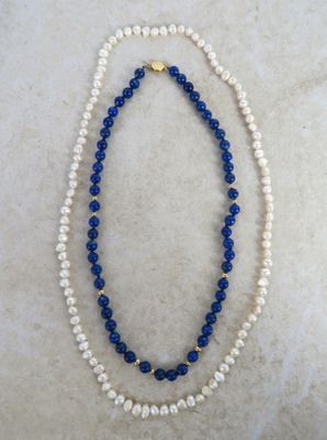 a white and blue beaded necklace on a marble surface