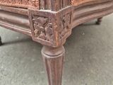 a close up of a wooden chair with a brown upholstered seat