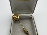 a small gold brooch in a box on a white surface