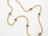a gold necklace with multi colored stones on a white background