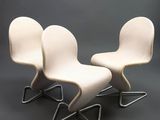 three white chairs sitting on top of each other on a gray surface