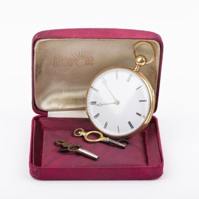 a gold pocket watch and a pair of scissors in a red case