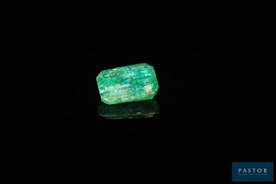 une pierre d'émeraude verte sur un fond noir