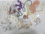 many different necklaces and bracelets laid out on a table