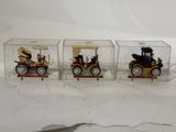 three small toy cars in a clear box on a white surface