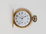 a gold pocket watch with a white face on a white surface