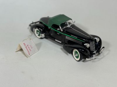 a black toy car with a green top on a white surface