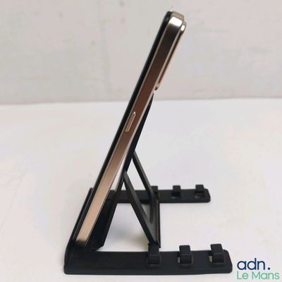 un téléphone portable posé sur un support sur une table