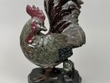 a statue of a rooster on a rock on a white background