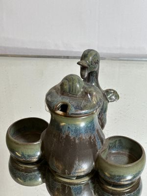 une photo représentant une théière et quatre tasses posées sur une table