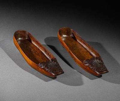 pair of carved wooden canoes on a gray surface