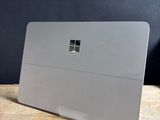 Un ordinateur portable Microsoft Surface posé sur une table en bois, sur fond noir