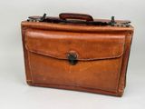 an old brown leather briefcase sitting on top of a white table