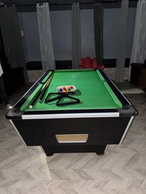 une table de billard recouverte d'un tapis vert, dans une pièce