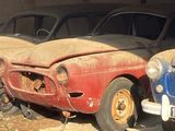 Plusieurs vieilles voitures sont garées en rangée dans un garage