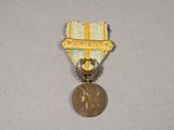 une petite médaille surmontée d'une médaille en or