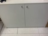 a white cabinet in the corner of a room with a phone on it
