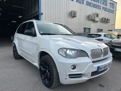Une BMW X5 blanche garée devant un immeuble