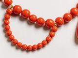 an image of a red necklace with a cross on a white surface
