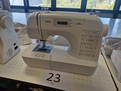 une machine à coudre blanche posée sur une table devant une fenêtre