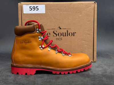 the sole of a pair of yellow hiking boots with red laces