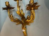 un bougeoir en or accroché au mur et orné de fleurs