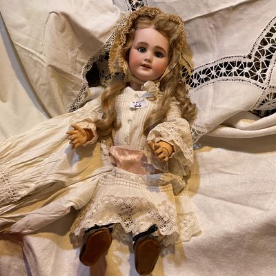 a doll that is sitting on a bed with a white sheet