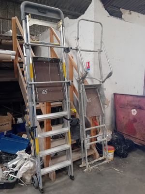 une échelle appuyée contre un mur, à côté d'une pile de cartons