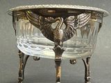 a glass bowl with a bird on it sitting on a stand