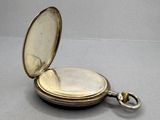 a silver pocket watch sitting on a table with a key