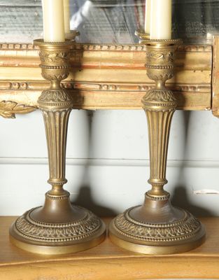two candles that are sitting on a shelf in front of a mirror