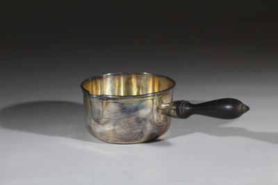 une tasse en argent avec une anse noire posée sur une table