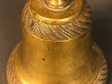 an antique brass bell on a table with a rope around it