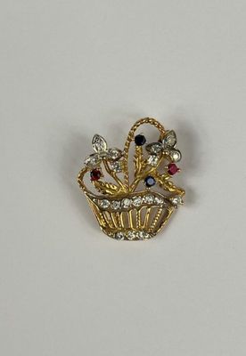 un gros plan d'une broche plaquée or représentant un panier de fleurs