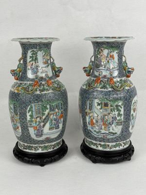 pair of chinese vases with figures on them sitting on a stand