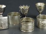 five silver cups and a silver vase on a table