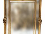 un grand miroir à cadre doré, orné de sculptures raffinées et d'un cadre décoratif