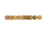 a close up of a gold bracelet with flowers on a white background