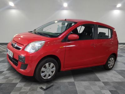 une voiture rouge est garée dans une pièce au sol en damier