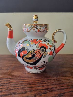 a tea pot with a bird on it sitting on a table