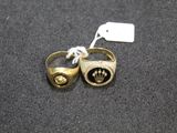 two gold rings with black stones on them on a black surface