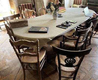 une longue table avec des chaises et un livre posé dessus