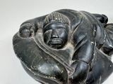 a black sculpture of a sleeping man on a white surface