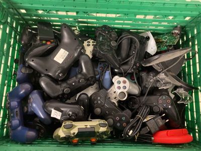 un panier vert rempli de manettes de jeux vidéo et de télécommandes