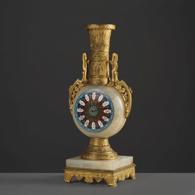 un vase décoré, doré et blanc, surmonté d'une horloge